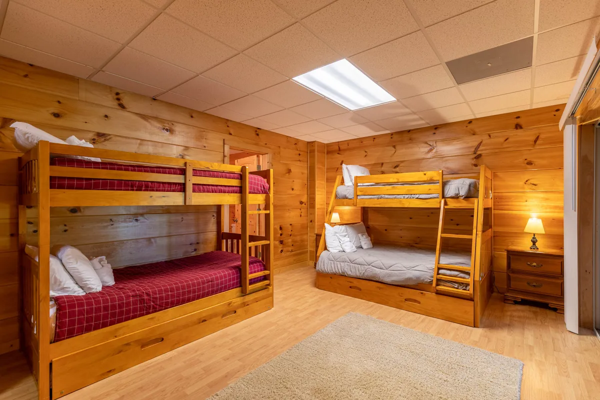 Double bunk beds stand ready for fun sleepovers, paired with a nightstand and soft area rug. The space suggests play and relaxation, designed for kids to enjoy games, stories, and private moments together.